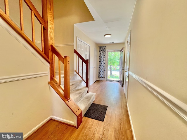 entrance foyer with light wood-style flooring, stairs, and baseboards