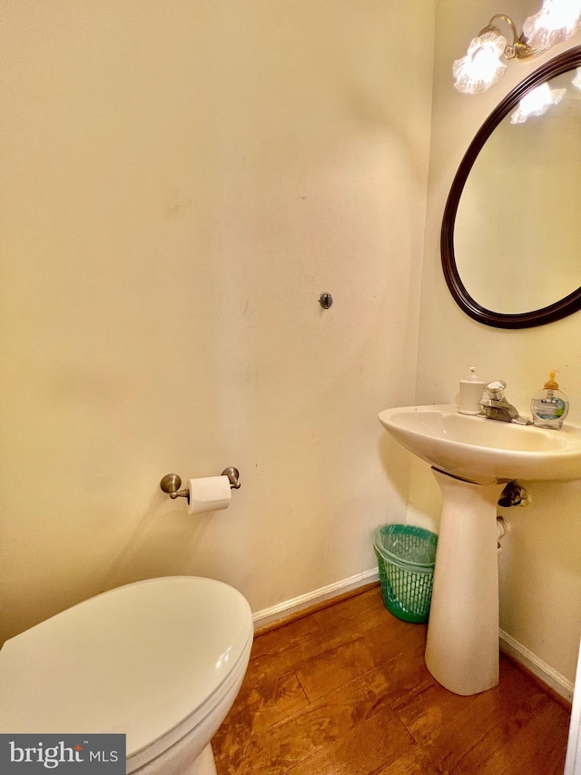 bathroom with baseboards, toilet, and wood finished floors
