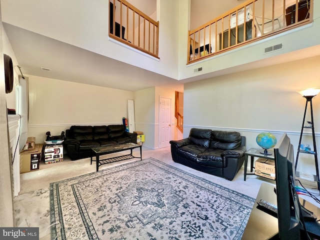 carpeted living room with visible vents and a towering ceiling