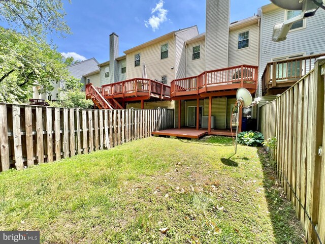 rear view of property featuring a yard, a wooden deck, and a fenced backyard