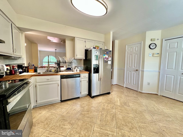kitchen with light tile patterned floors, a sink, decorative backsplash, stainless steel appliances, and white cabinets