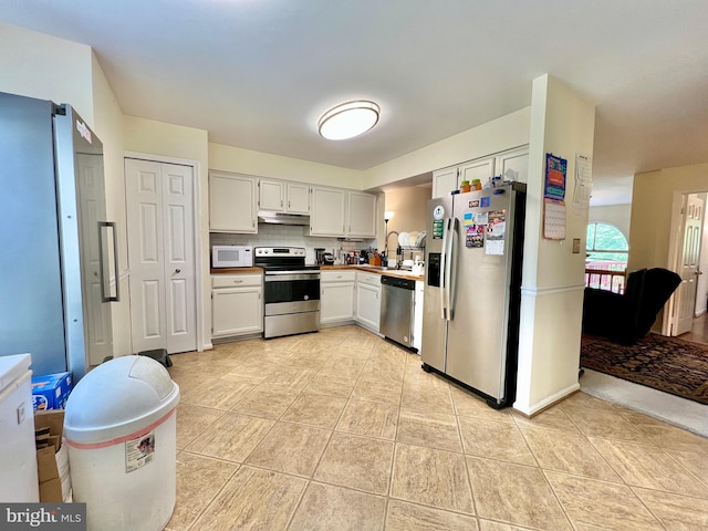kitchen with under cabinet range hood, light tile patterned floors, light countertops, tasteful backsplash, and appliances with stainless steel finishes