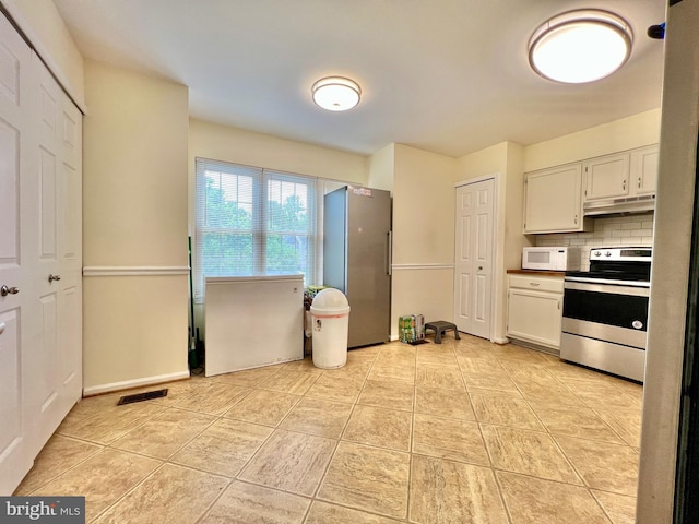 kitchen featuring stainless steel appliances, visible vents, under cabinet range hood, decorative backsplash, and light tile patterned floors