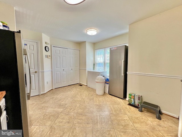 interior space featuring freestanding refrigerator and light tile patterned floors