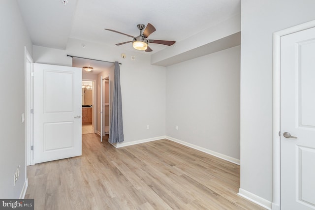 unfurnished bedroom with connected bathroom, baseboards, a ceiling fan, and light wood-style floors