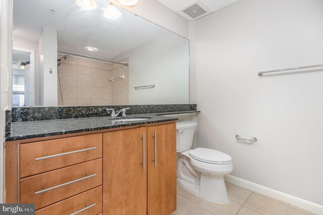 bathroom with tile patterned flooring, toilet, vanity, baseboards, and a shower