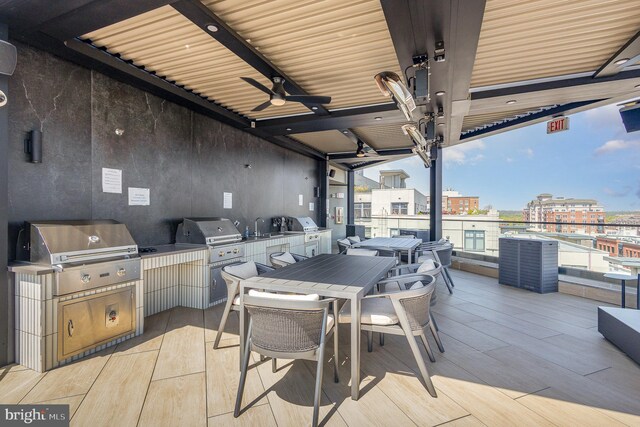 view of patio / terrace with a grill, ceiling fan, outdoor dining space, and exterior kitchen