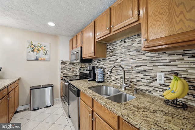 kitchen with stainless steel appliances, a sink, light tile patterned flooring, decorative backsplash, and a textured ceiling