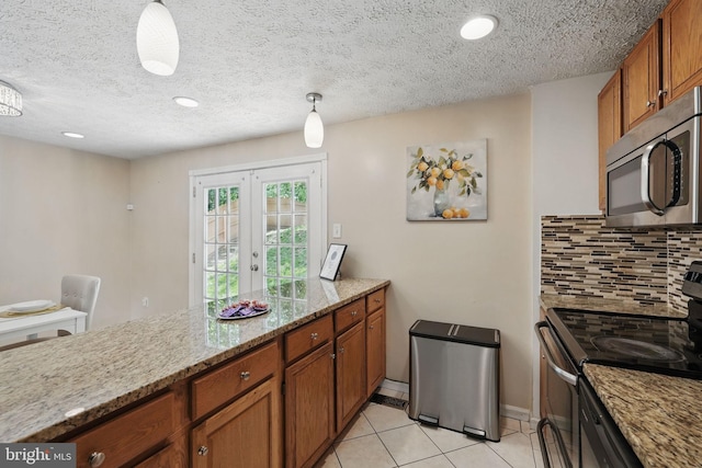 kitchen featuring appliances with stainless steel finishes, brown cabinetry, backsplash, light tile patterned floors, and french doors