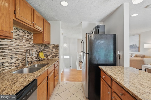 kitchen featuring a sink, stainless steel appliances, light tile patterned floors, a textured ceiling, and decorative backsplash