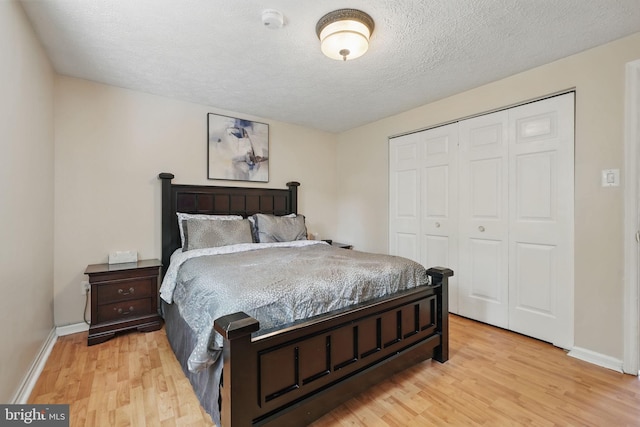 bedroom featuring light wood-style floors, a closet, baseboards, and a textured ceiling