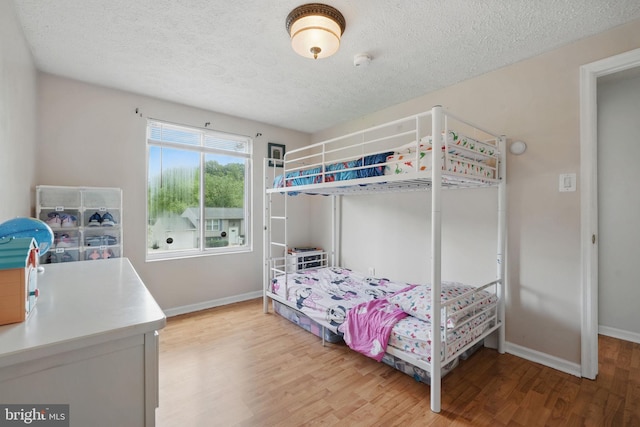 bedroom featuring light wood-style flooring, baseboards, and a textured ceiling