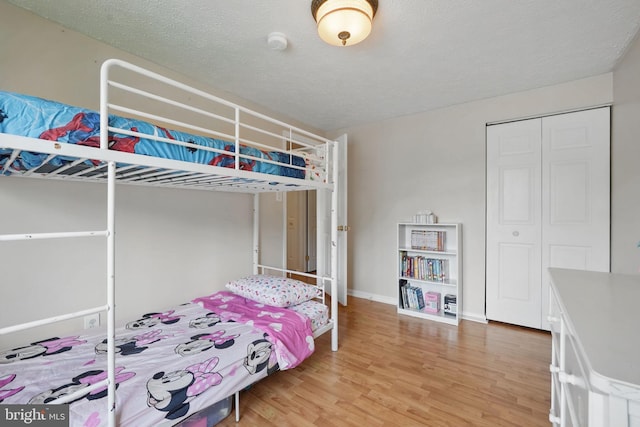 bedroom with light wood-style flooring, a closet, and baseboards