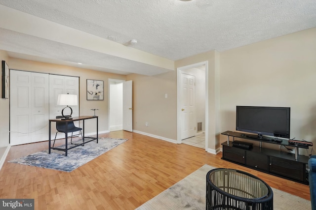 office area with wood finished floors, a textured ceiling, and baseboards
