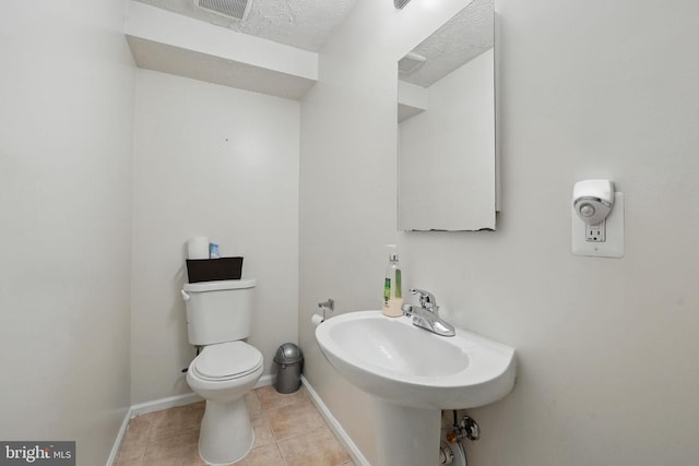bathroom featuring tile patterned floors, toilet, a sink, baseboards, and a textured ceiling