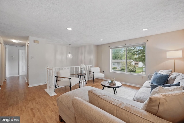 living room with a textured ceiling, light wood-style flooring, baseboards, and recessed lighting
