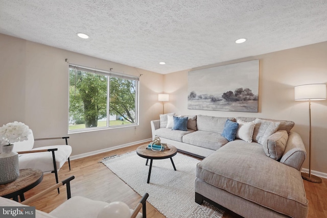 living room with a textured ceiling, baseboards, recessed lighting, and wood finished floors