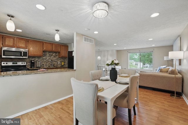 dining room with light wood-style flooring, recessed lighting, baseboards, and a chandelier