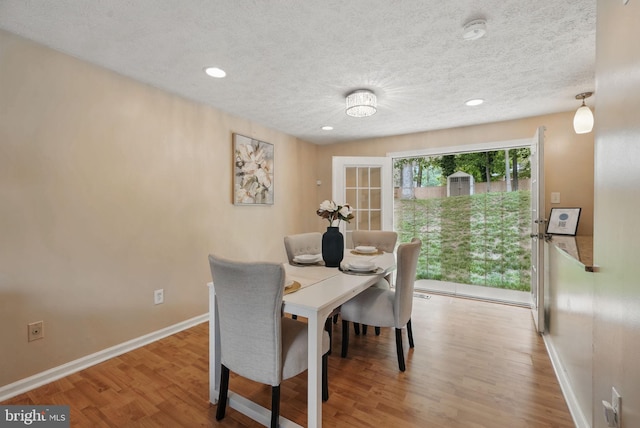 dining area with wood finished floors, a textured ceiling, baseboards, and recessed lighting