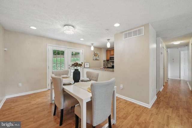 dining room with light wood-style floors, baseboards, a textured ceiling, recessed lighting, and french doors