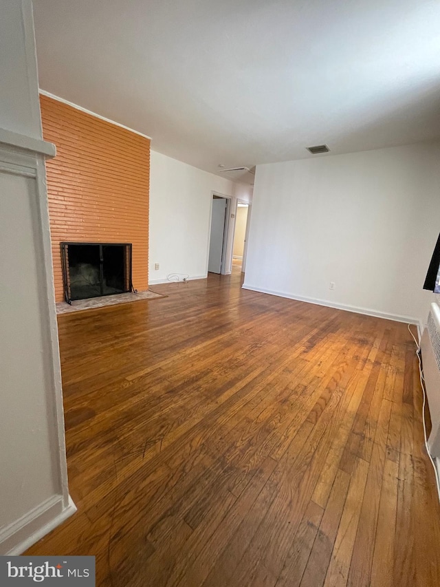 unfurnished living room with visible vents, baseboards, hardwood / wood-style flooring, and a fireplace