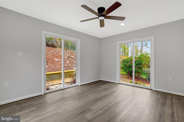 empty room featuring wood finished floors, ceiling fan, baseboards, and a wealth of natural light