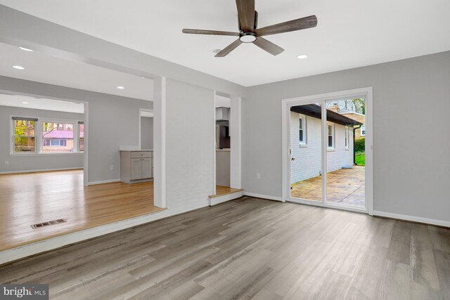 unfurnished living room with visible vents, ceiling fan, wood finished floors, and baseboards