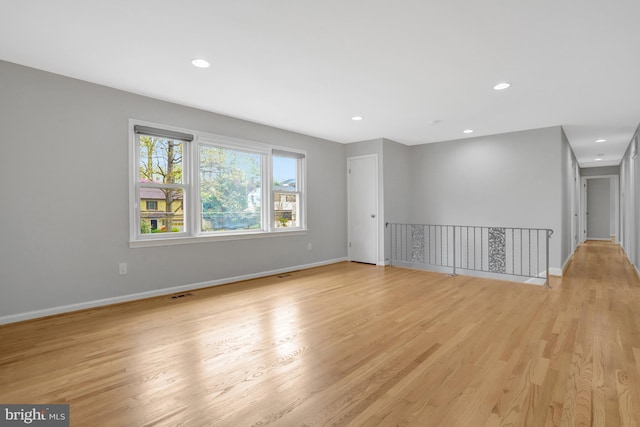 empty room featuring light wood-style floors, baseboards, visible vents, and recessed lighting