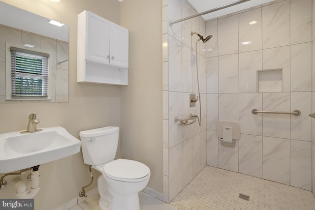full bathroom featuring toilet, tiled shower, and a sink