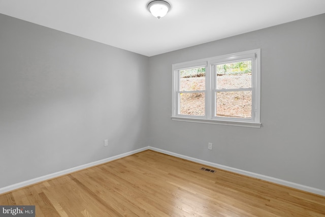 unfurnished room with light wood-type flooring, visible vents, and baseboards