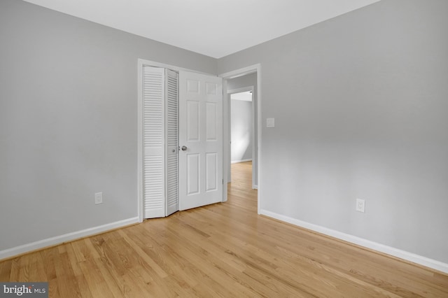 unfurnished bedroom featuring a closet, baseboards, and wood finished floors