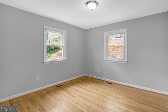 unfurnished room featuring visible vents, baseboards, and wood finished floors