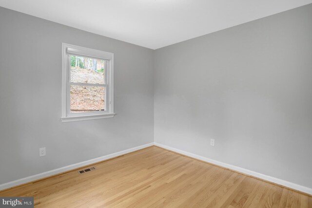 spare room featuring visible vents, baseboards, and wood finished floors