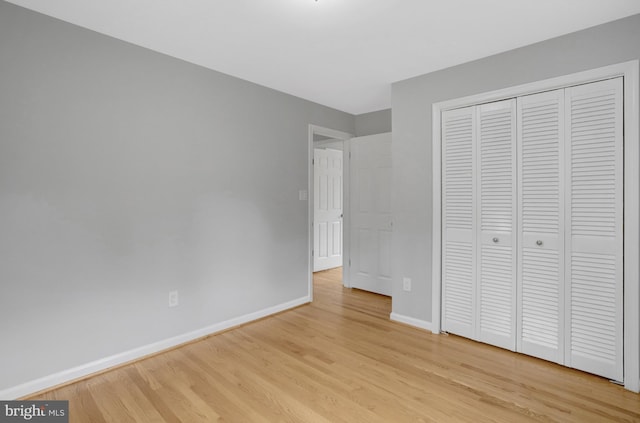 unfurnished bedroom with light wood-style floors, a closet, and baseboards