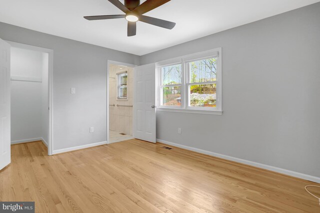 unfurnished bedroom featuring a closet, baseboards, a spacious closet, light wood-style floors, and visible vents