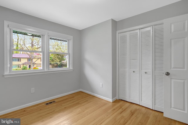 unfurnished bedroom featuring light wood-style flooring, multiple windows, and visible vents