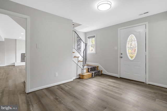 entrance foyer with stairway, visible vents, baseboards, and wood finished floors