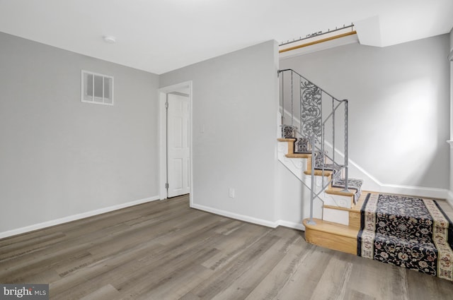 staircase with visible vents, baseboards, and wood finished floors