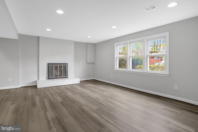 unfurnished living room featuring visible vents, recessed lighting, wood finished floors, a brick fireplace, and baseboards