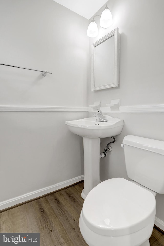 bathroom with baseboards, toilet, and wood finished floors
