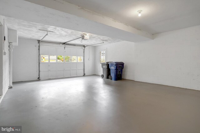 garage featuring concrete block wall and a garage door opener