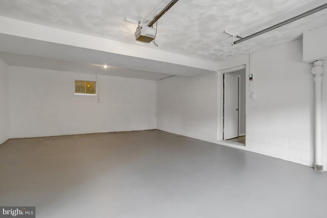 garage with a garage door opener and concrete block wall