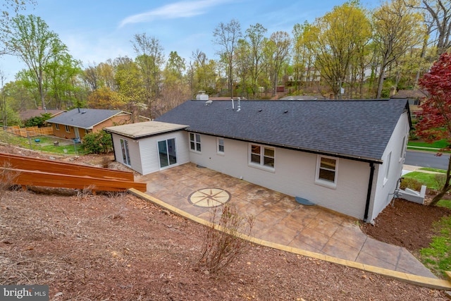 back of property with roof with shingles, a patio, and fence