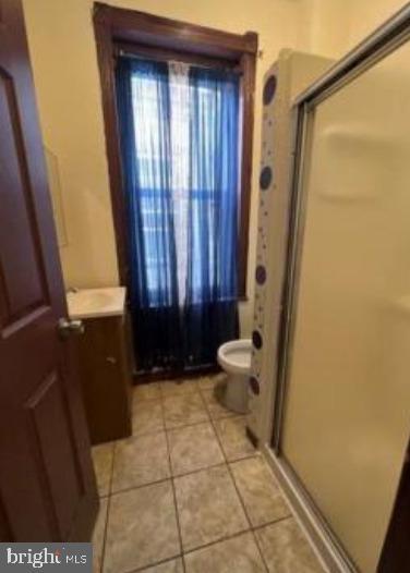 bathroom featuring a shower stall, tile patterned flooring, vanity, and toilet