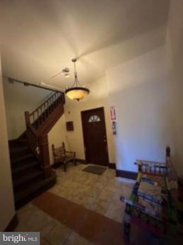 entryway featuring tile patterned flooring, vaulted ceiling, and stairway