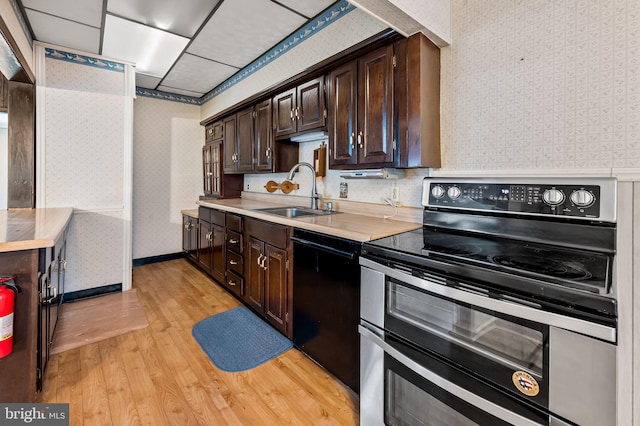 kitchen featuring a sink, double oven range, wallpapered walls, and dishwasher