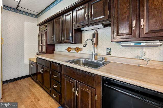 kitchen featuring light wood-style flooring, dishwasher, dark brown cabinets, a sink, and light countertops