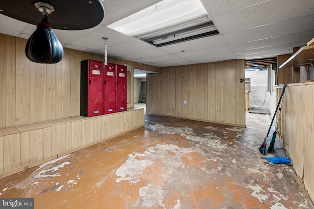 finished basement with a paneled ceiling and wooden walls
