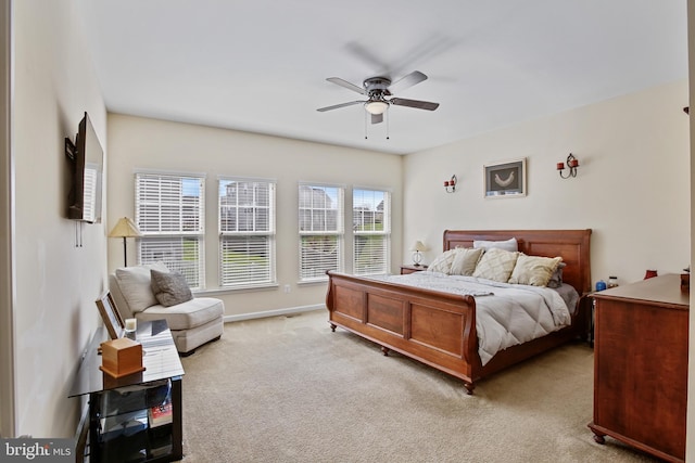 bedroom featuring light colored carpet, baseboards, and a ceiling fan