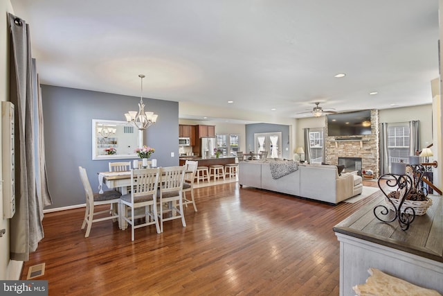 dining room with visible vents, recessed lighting, ceiling fan with notable chandelier, a fireplace, and dark wood-type flooring